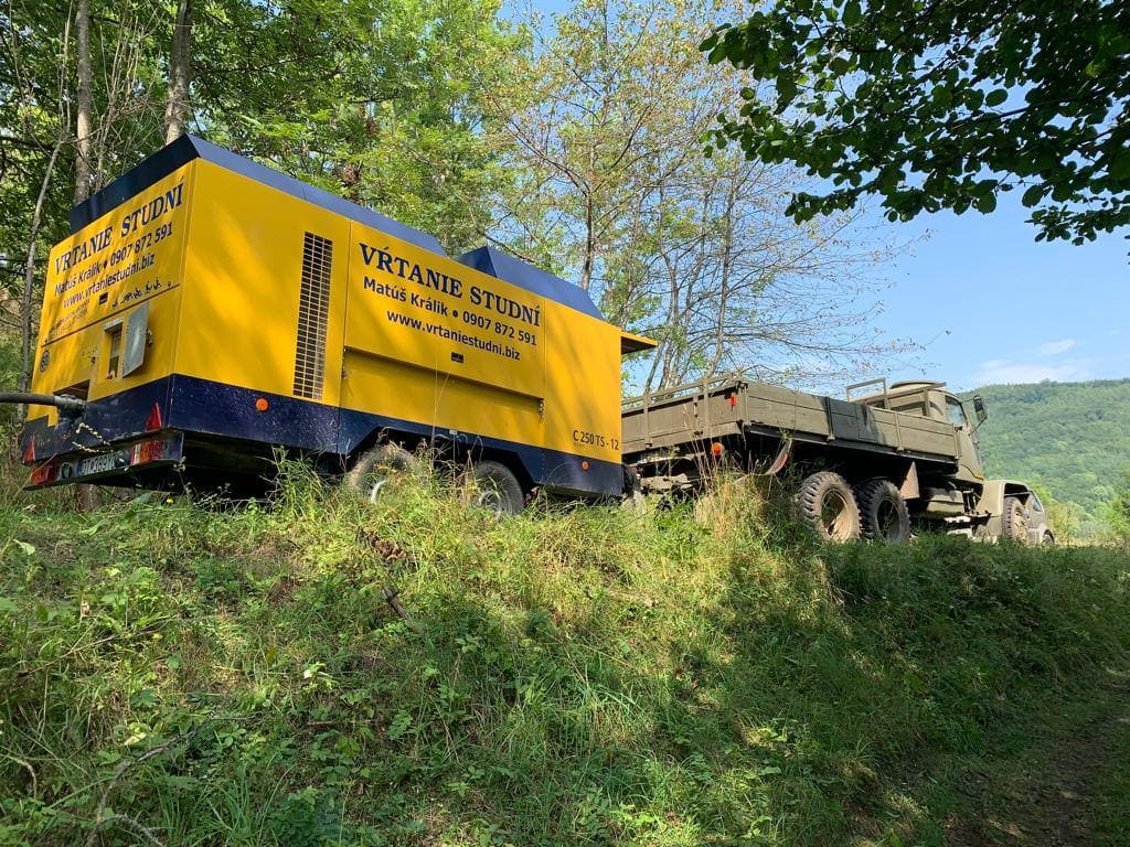 Kompresor a nákladné auto s vrtnou technikou na pozemku